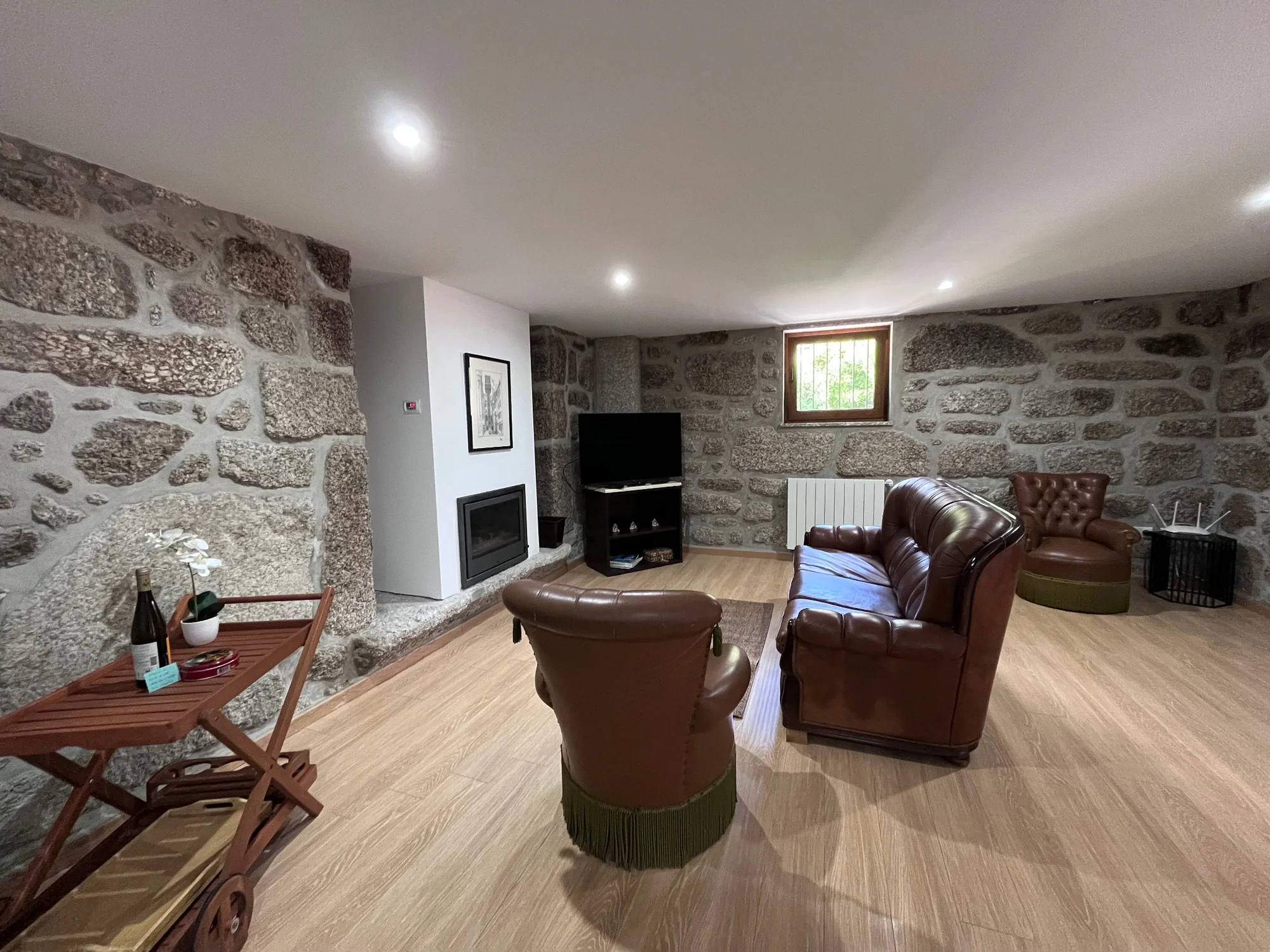 Sala em pedra com lareira e sofás de couro